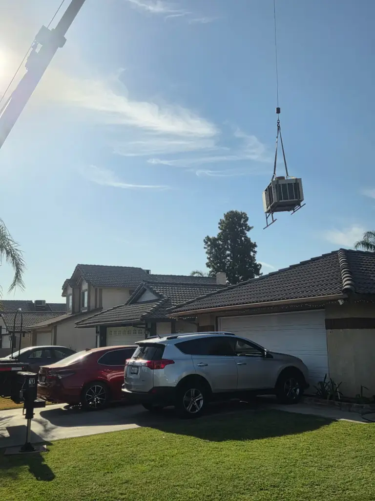 Crane lifting a rooftop HVAC unit for a Palmer installation in Bakersfield