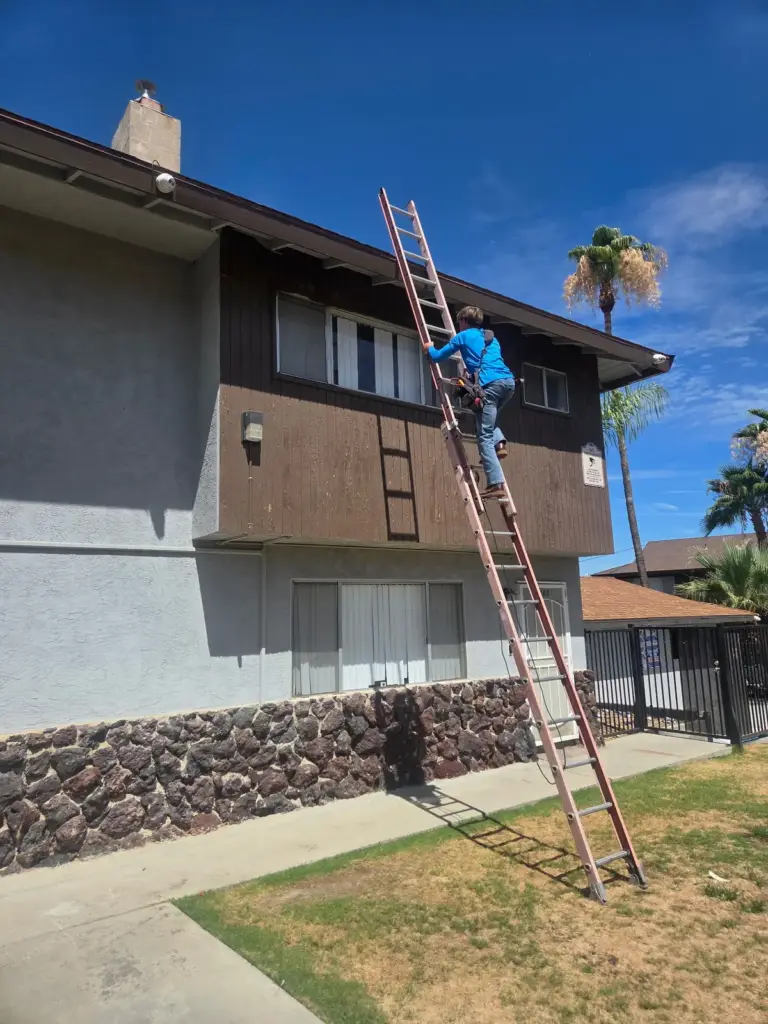 Palmer technician on a ladder working on ductwork at a Bakersfield building